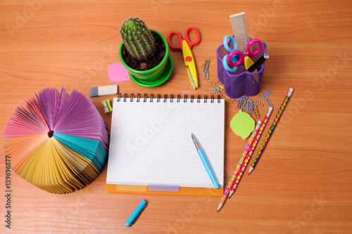 Top view of office tools with blank notebook on wooden table