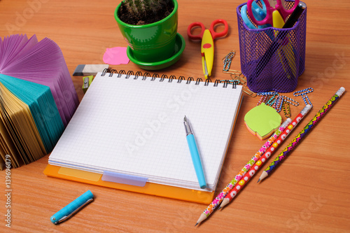 Top view of office tools with blank notebook on wooden table