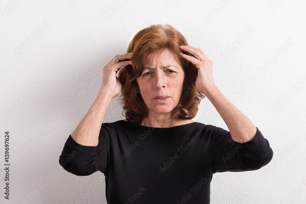 Senior woman in black t-shirt, studio shot against white wall. Senior woman in black t-shirt, studio shot against white wall.