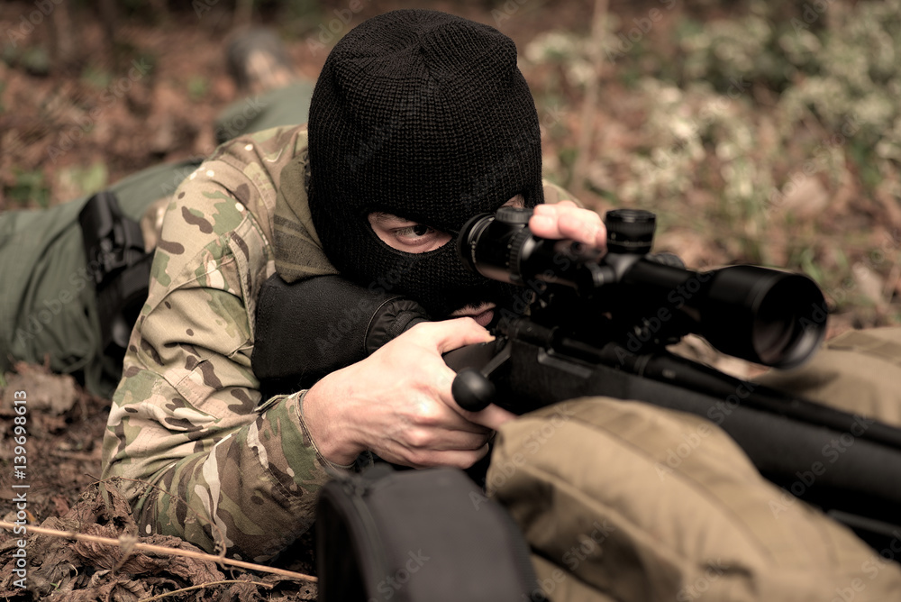 Fototapeta premium vermummter Mann mit Gewehr