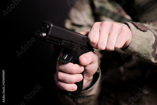 Mann in Tarnkleidung hält eine Pistole 