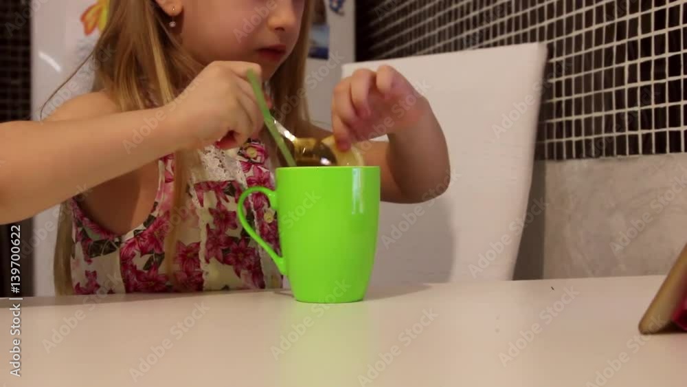 Cute little girl is having a breakfast. Child eating lemon and drinking tea. Cute little girl is having a breakfast. Child eating lemon and drinking tea.