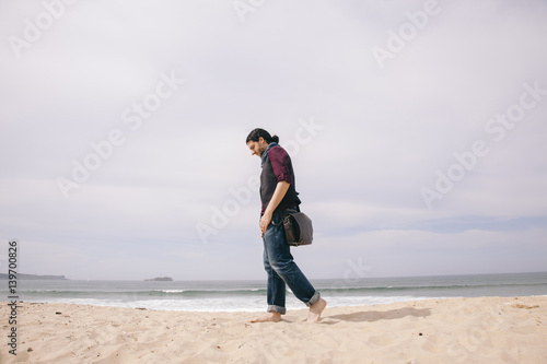 caucasian hipster man walking alone on the beach with casual clothes © beavera