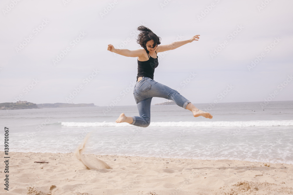 young cheerful woman jumping on the beach