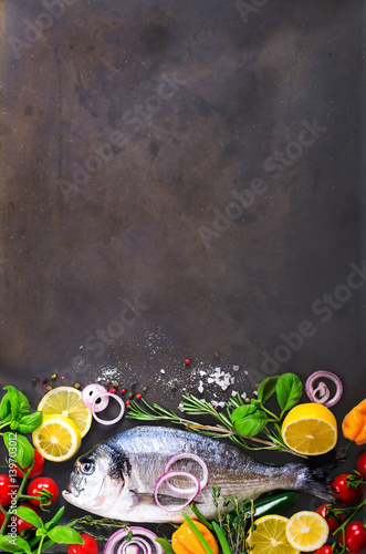 Fresh uncooked fish, dorado, sea bream with lemon, herbs, vegetables and spices on stone background. Top view. Banner