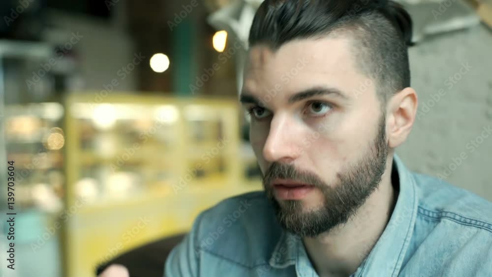 Handsome man with hipster bun sitting in the cafe and drinking coffee
Handsome man with hipster bun sitting in the cafe and drinking coffee
