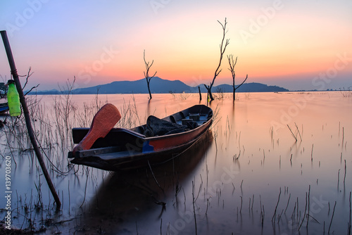 Alone fishing boat at lake with sunrise