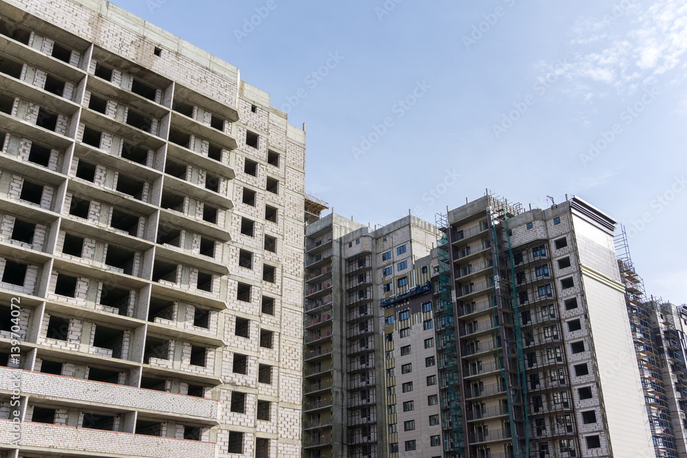 Facade of construction at background of blue sky, development of modern city con Facade of construction at background of blue sky, development of modern city con