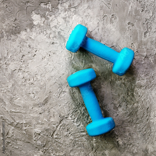Fitness concept. Turquoise dumbbells and yellow measuring tape. Copyspace