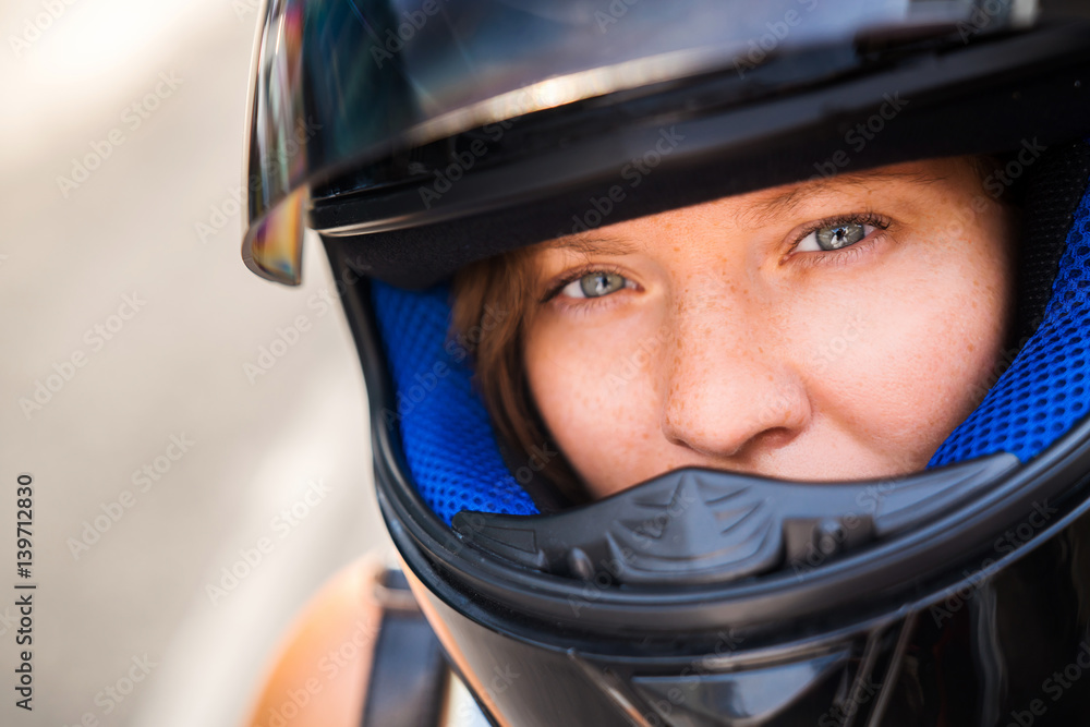 The concept of safe driving. Portrait of a girl with freckles close-up in a motorcycle helmet, serious look into the camera. The concept of safe driving. Portrait of a girl with freckles close-up in a motorcycle helmet, serious look into the camera.