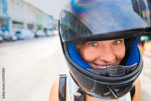 Portrait of a girl close-up of a head in a helmet with an open glass. Happy girl in helmet with good mood on a street background in the afternoon. © galaganov