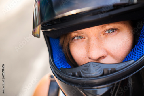 The concept of safe driving. Portrait of a girl with freckles close-up in a motorcycle helmet, serious look into the camera. © galaganov