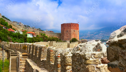 фотографія View of Red Tower (Kizil Kule) and ancient stone wall of Alanya Castle