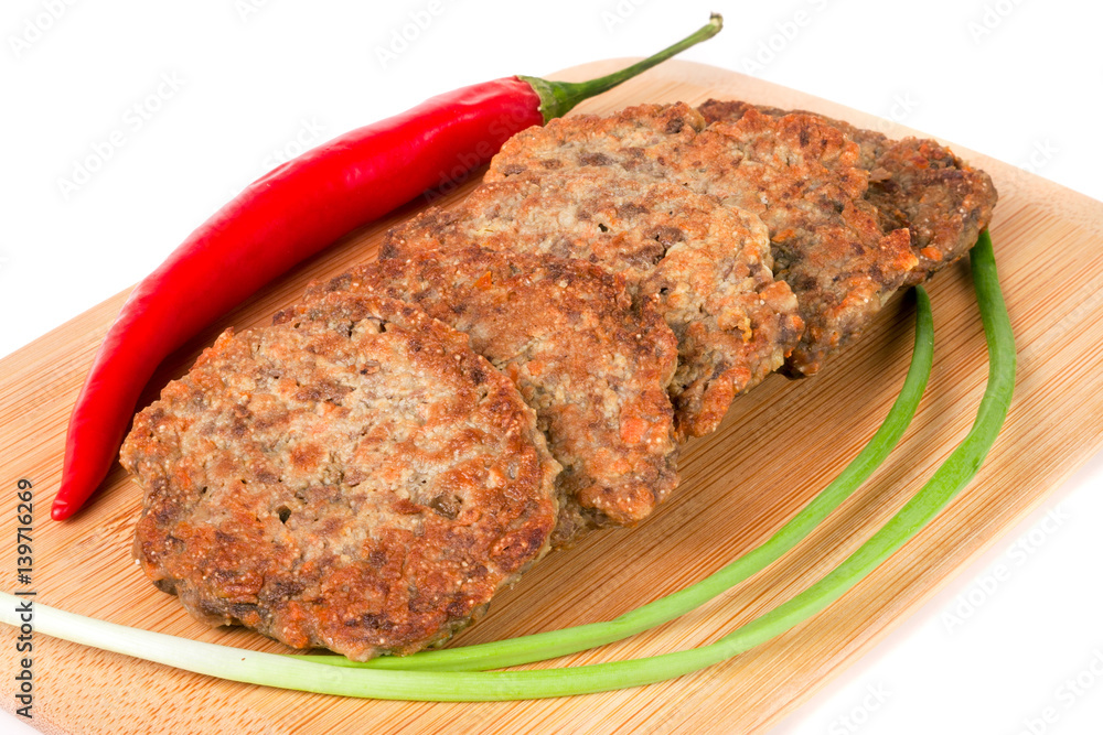 liver pancakes or cutlets with chilli and spring onions on a cutting board isolated white background