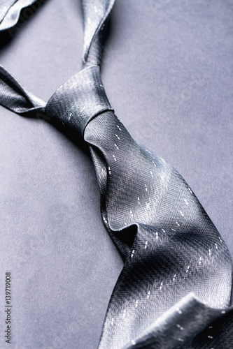 Gray spotted man's knotted tie over gray background