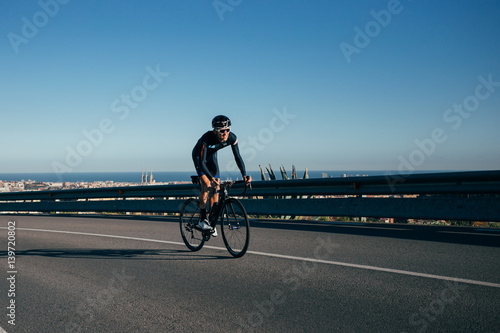 A fit strong cyclist climbs a road overlooking Barcelona, spain