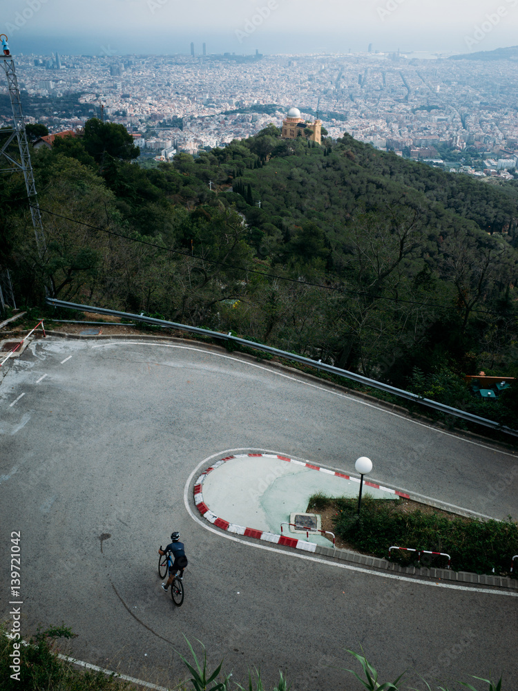 Obraz premium A professional cyclist descending a technical corner near tibidabo park, high above barcelona, spain