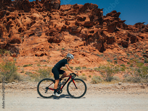 Cute female cyclist riding near sand rocks in nevada desert in the summer