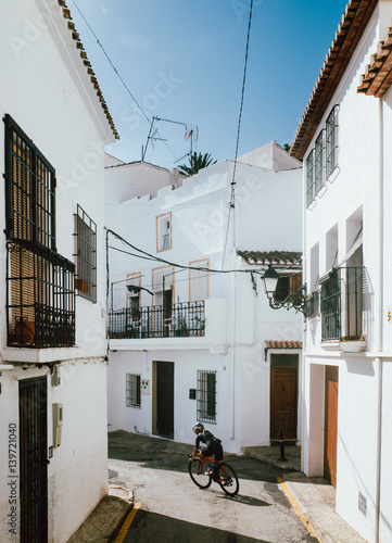 A young female cyclist cornering through the narrow cobbled streets of an old town in Altea, Spain