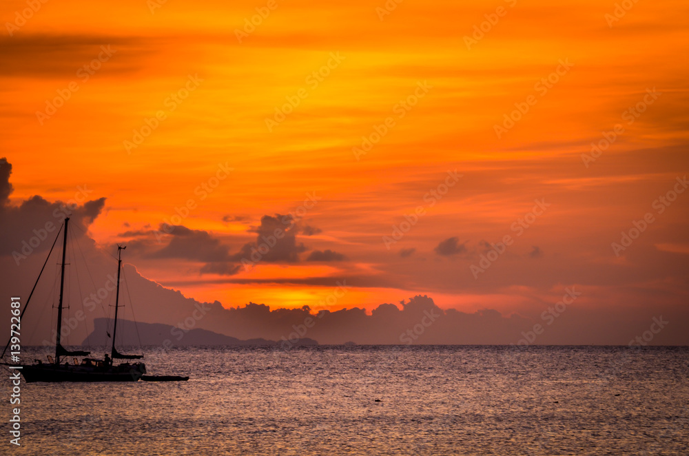 tropical sunset with silhouette of boat