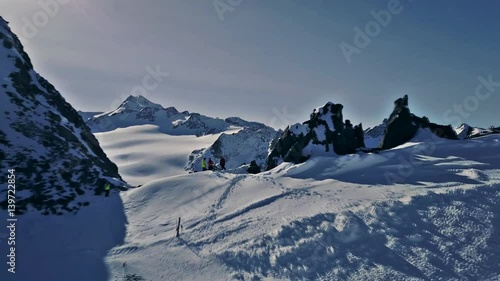 Aerial view on a group of people standing on top of mountain and having a picnic there. Scenic panorama of valley appears. Ski lift and skiers on background. Solden, Austria