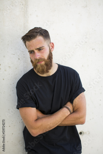 Bearded man posing in the street with crossed arms. © juananbarros