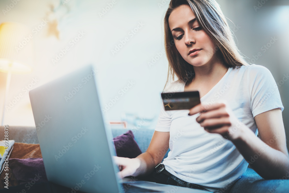 Young hipster girl holding credit or debit card to pay online via laptop, internet shop concept, online payment, internet banking Young hipster girl holding credit or debit card to pay online via laptop, internet shop concept, online payment, internet banking