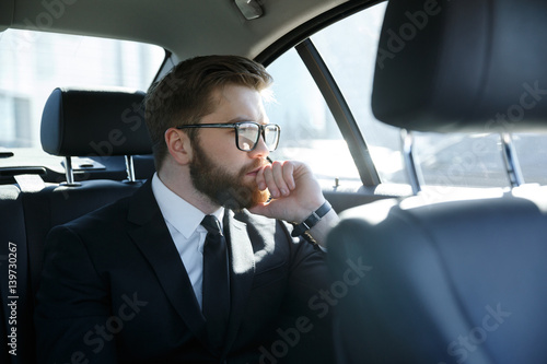 Man in eyeglasses sitting at the back seat of car © Drobot Dean
