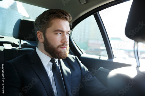 Man in suit sitting at the back seat of car © Drobot Dean