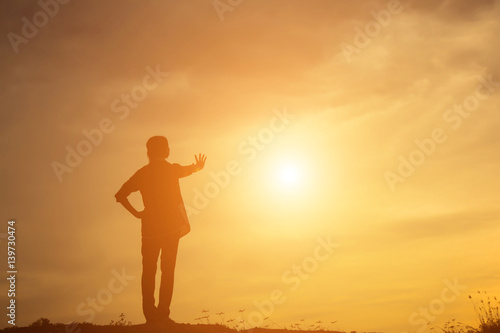 Silhouette of woman praying over beautiful sky background