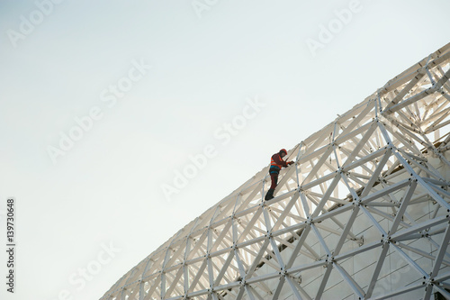 Photos man in overalls  builder fixes on the height