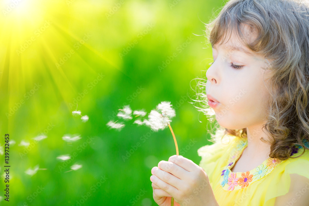 Happy child blowing dandelion flower outdoors Happy child blowing dandelion flower outdoors