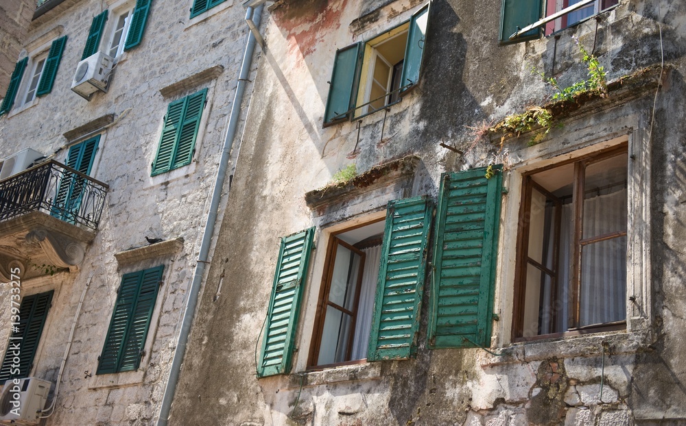 Old Mediterranean house and facade in the town of Kotor, Montenegro.  Walls of building,  windows with open and closed shutters. Climate control air-conditioning 