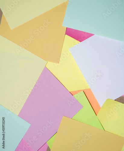 Multi coloured note paper on a wooden background 
