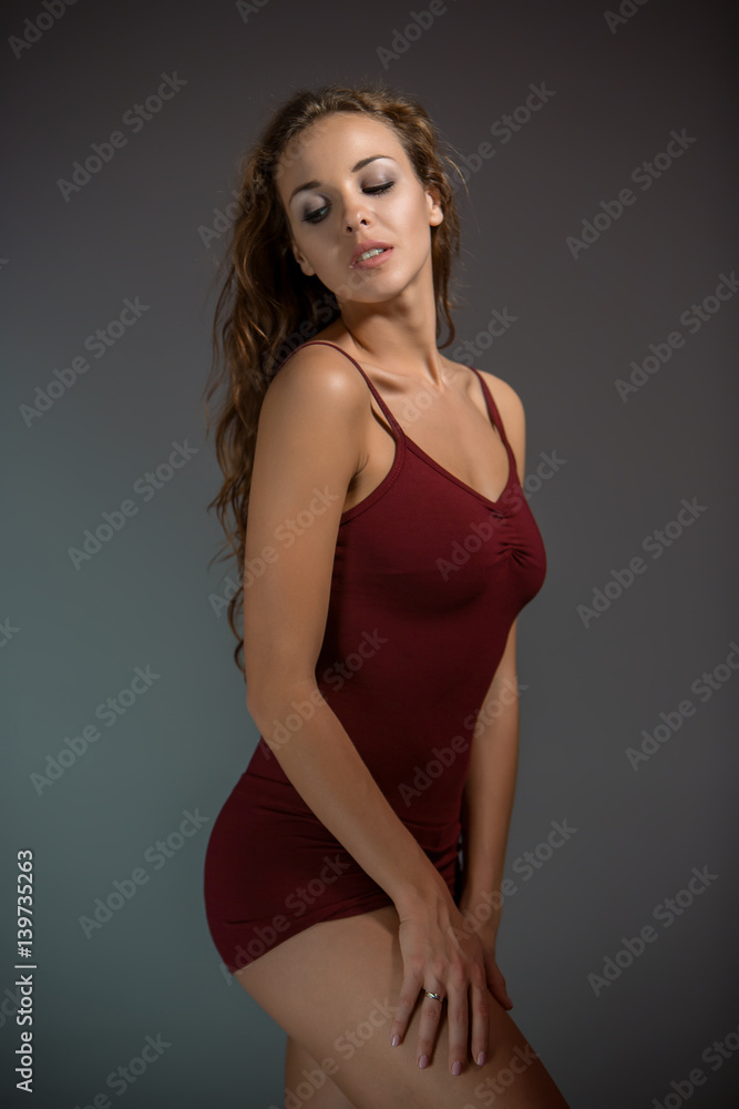 Young beautiful woman in red T-shirt and shorts dancing on a dark gray studio background Young beautiful woman in red T-shirt and shorts dancing on a dark gray studio background