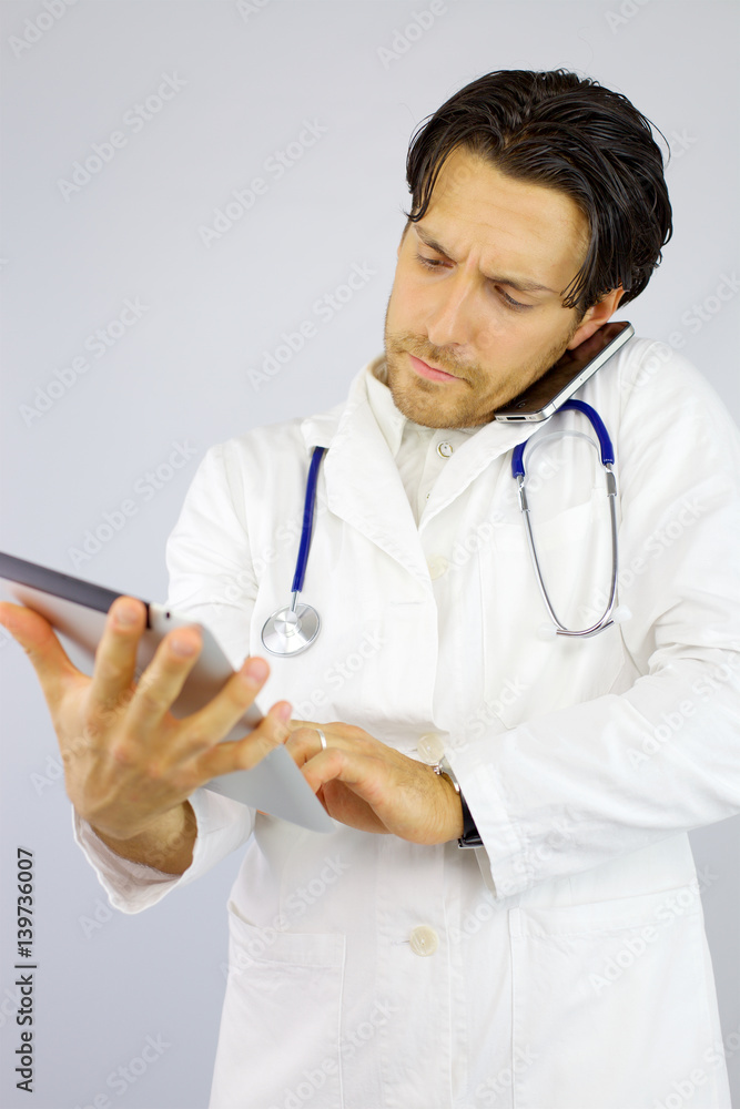 Handsome doctor on the phone while working with tablet Handsome doctor on the phone while working with tablet