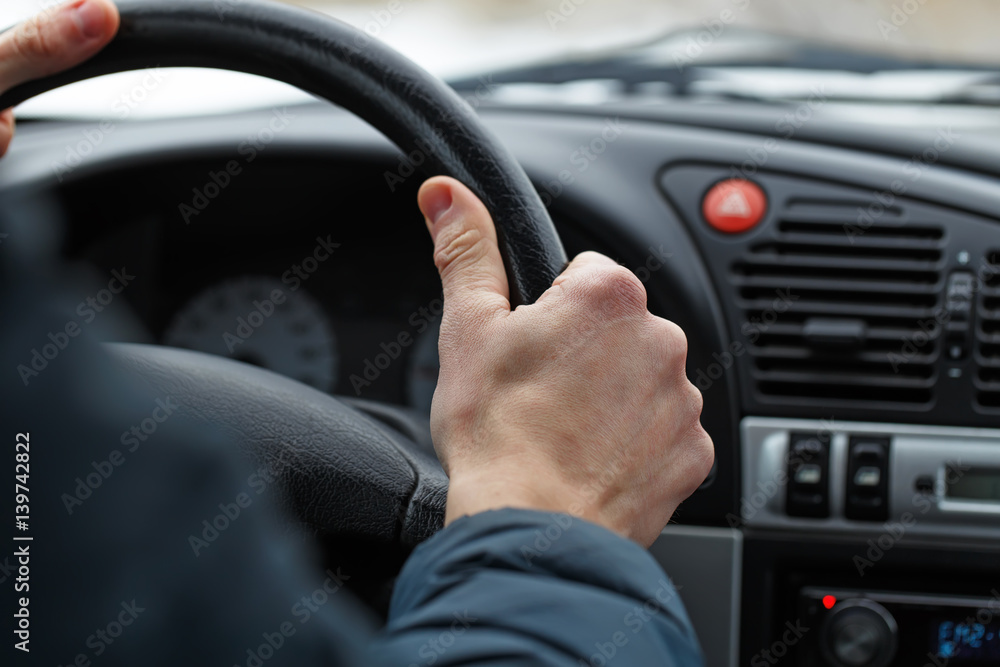 Naklejka premium Male hand on a steering wheel