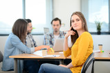 portrait of young woman in casual wear working in a creative business startup company office with coworker people in background