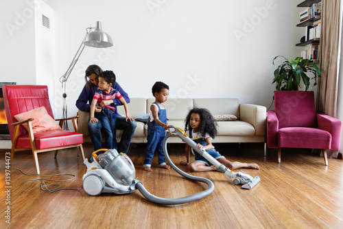 Une famille passe l'aspirateur dans le salon