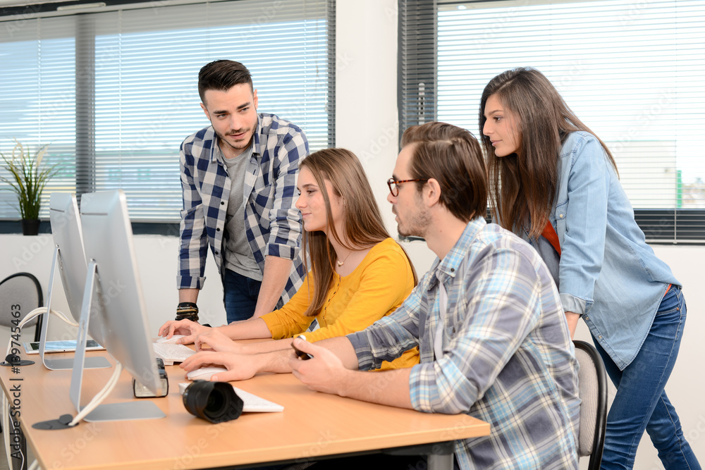 Fototapeta premium group of young cool hipster creative business people in casual wear working together in a meeting room of startup company looking at photography on computer