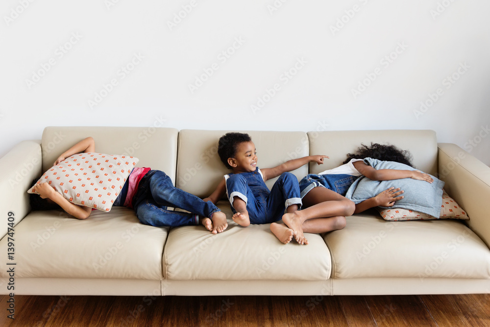 Trois enfants jouent à cache-cache sur le canapé Trois enfants jouent à cache-cache sur le canapé