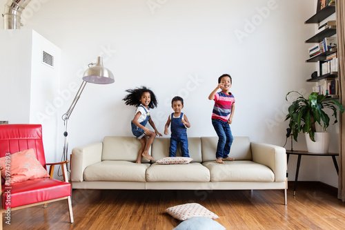 Trois enfants sautent sur le canapé du salon photo