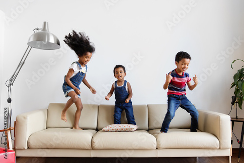 Trois enfants dansent sur le canapé du salon