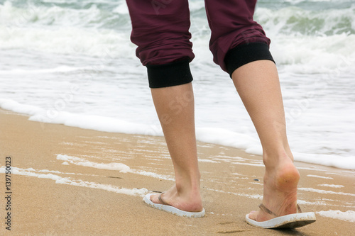 the girl's legs walking on the beach