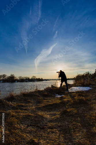 Professional photographer taking a photo flooding river at sunset 