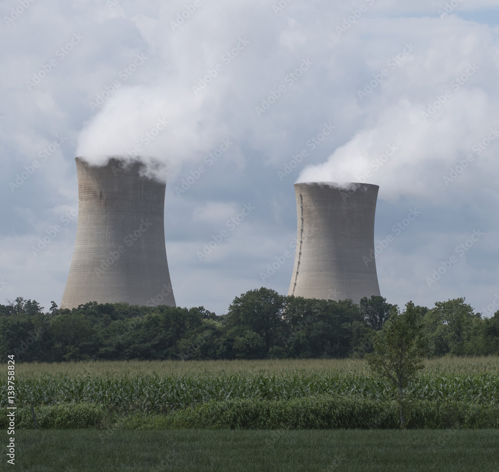 Water vapor from two boiling water reactor units of Limerick nuclear power plant near Philadelphia merges with blue cloud filled sky.. Green grass and trees are in the foreground. Water vapor from two boiling water reactor units of Limerick nuclear power plant near Philadelphia merges with blue cloud filled sky.. Green grass and trees are in the foreground.