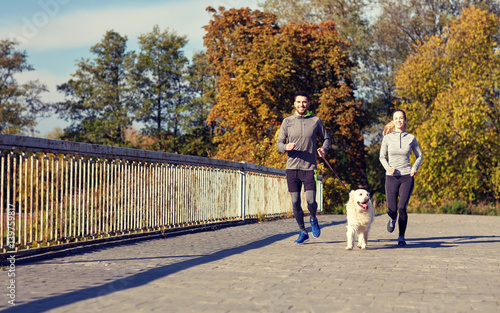 happy couple with dog running outdoors