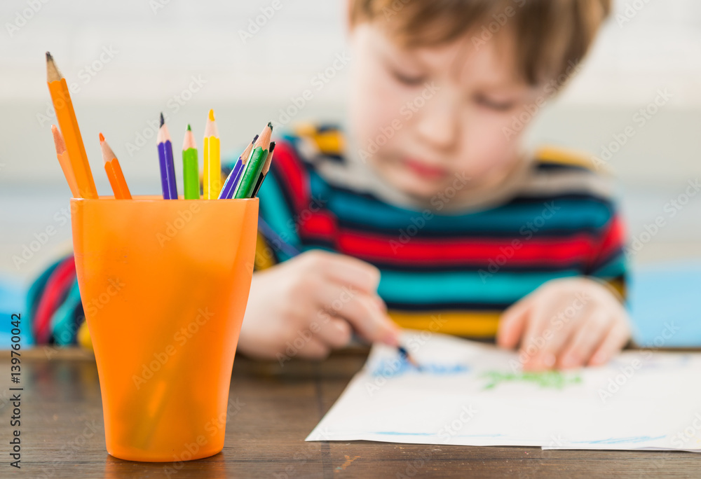 colorful pencils in jar with boy drawing on background colorful pencils in jar with boy drawing on background