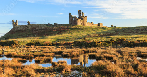Dunstanburgh Castle, Northumberland, with reflections in pond.