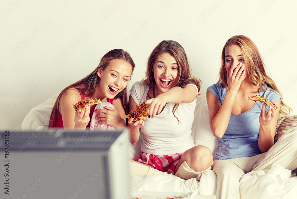 happy friends eating pizza and watching tv at home